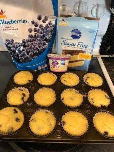 blueberry cupcakes in a muffin tin with yogurt on the side