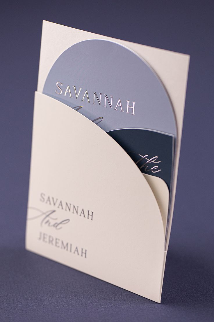 a close up of a business card on a blue surface with the word savannah in silver