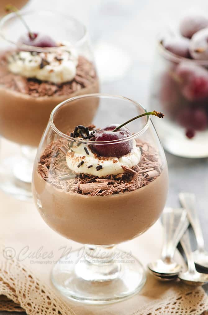 two glasses filled with dessert on top of a table