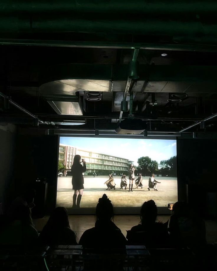 people are sitting in front of a large screen