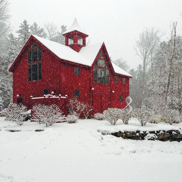 a red barn in the middle of winter with snow on it's roof and windows