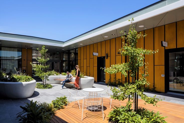 a woman sitting on a white couch in front of a yellow building with potted plants