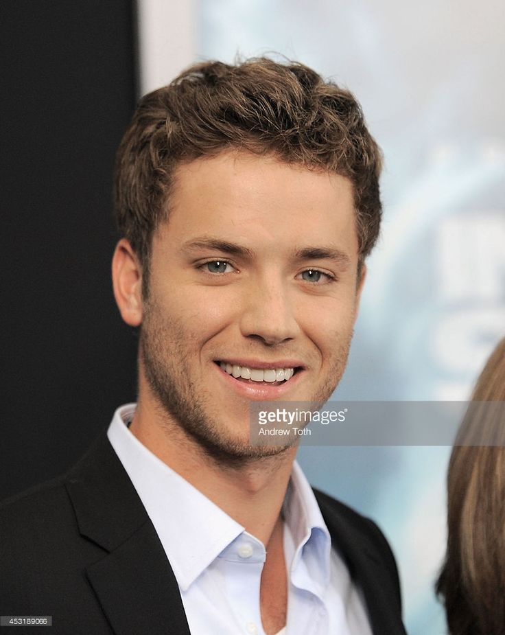 a smiling young man in a black suit and white shirt at the world premiere of his movie