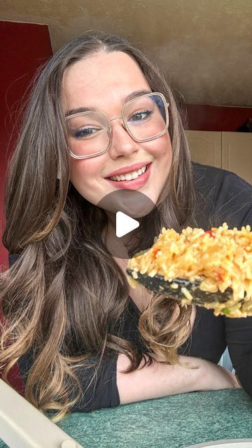 a woman with glasses holding up a plate of food in front of her face and smiling at the camera