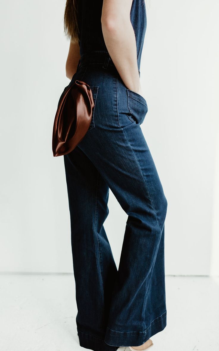 Saddle up in style with our Long Flared Denim Jumpsuit. Its flattering silhouette and tan contrast stitching add Western vibes to any outfit. Perfectly paired with boots and a cowboy hat for a playful, unique look. Yee-haw! Spring Flare Jeans With Contrast Stitching In Medium Wash, Dark Wash Denim Flare Jeans For Rodeo, Denim Bottoms With Contrast Stitching For Fall, Brown Denim Flare Jeans For Fall, Fall Denim Bottoms With Contrast Stitching, Retro Dark Wash Flare Jeans For Fall, Classic Brown Denim Bottoms, Casual Medium Wash Flare Jeans With Contrast Stitching, Fitted High Rise Western Flare Jeans