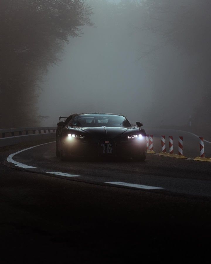 a black sports car driving on a foggy road