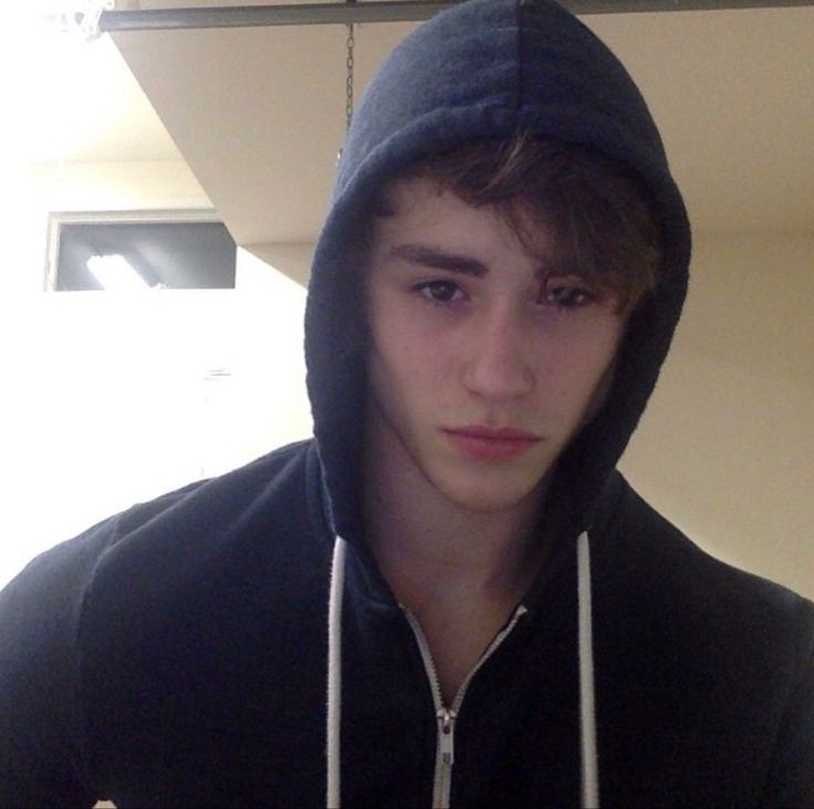 a young man in a black hoodie is looking at the camera