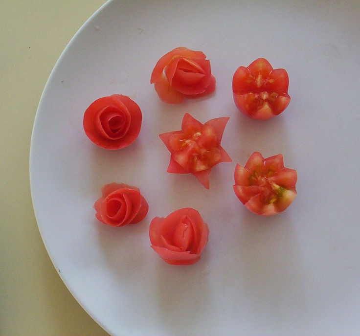 small red flowers on a white plate with one flower cut in half and four petals placed next to each other