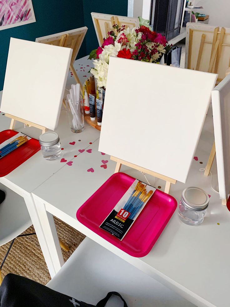 two easels are sitting on a table with flowers and other items in front of them