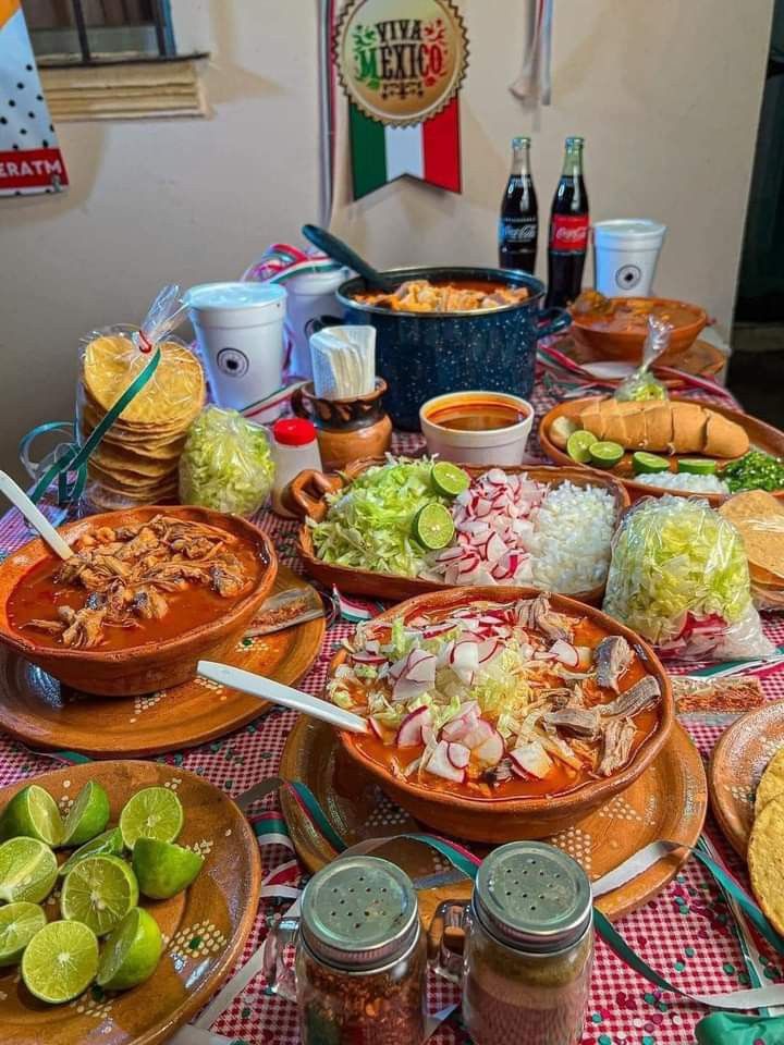 a table full of mexican food and condiments on the table with bottles of beer