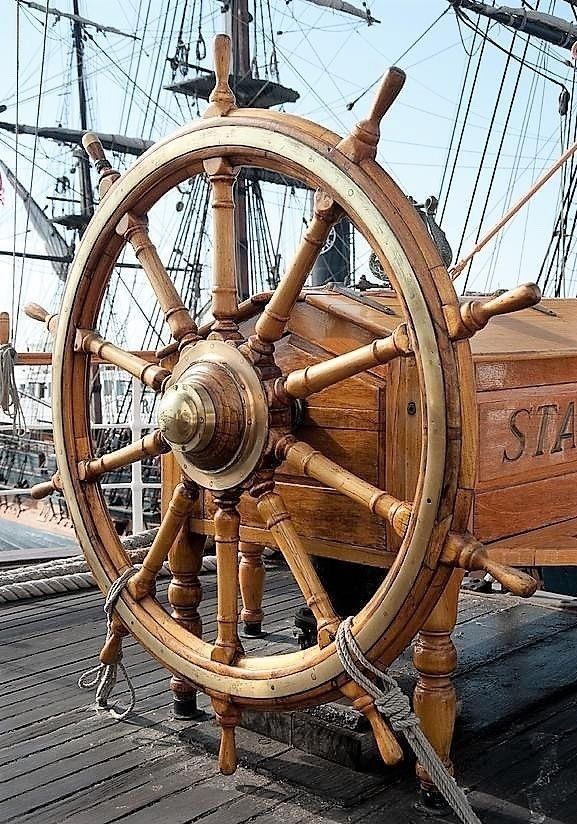 an old wooden ship steering wheel on the deck