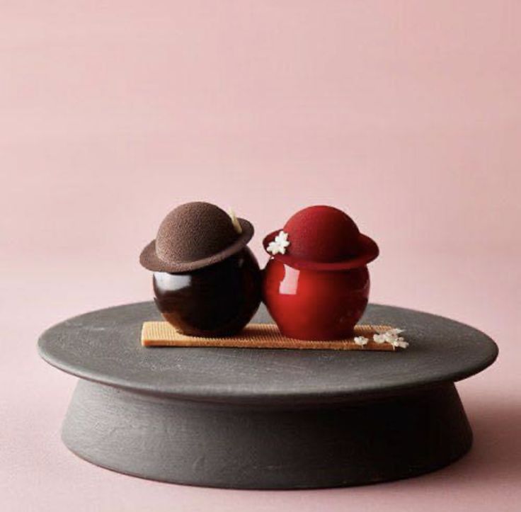 two small objects sitting on top of a round plate with a pink wall in the background