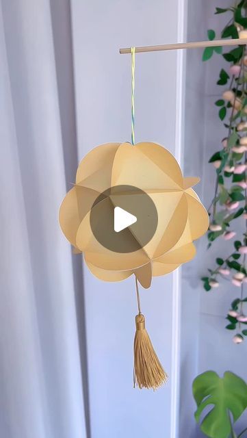 an origami flower mobile hanging from a pole with a video playing on it