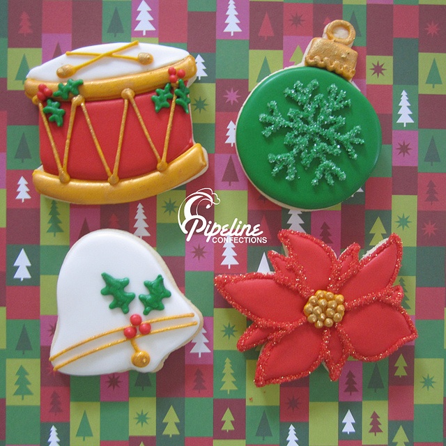 three decorated christmas cookies sitting on top of a colorful table cloth with trees and snowflakes