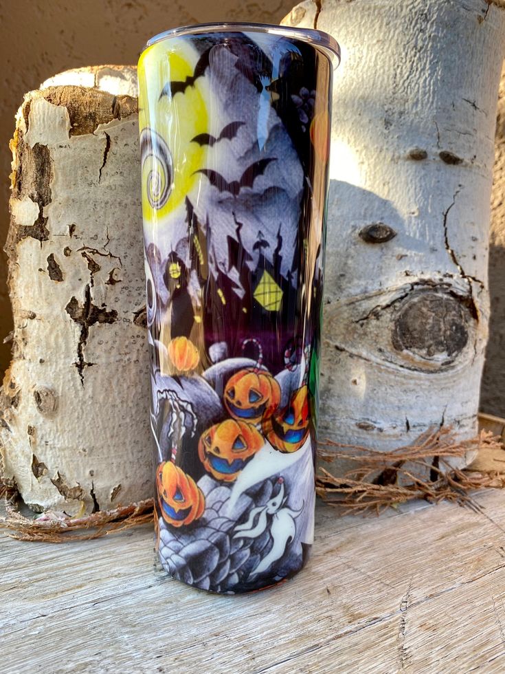 a colorful glass vase sitting on top of a wooden table next to two white birch trees