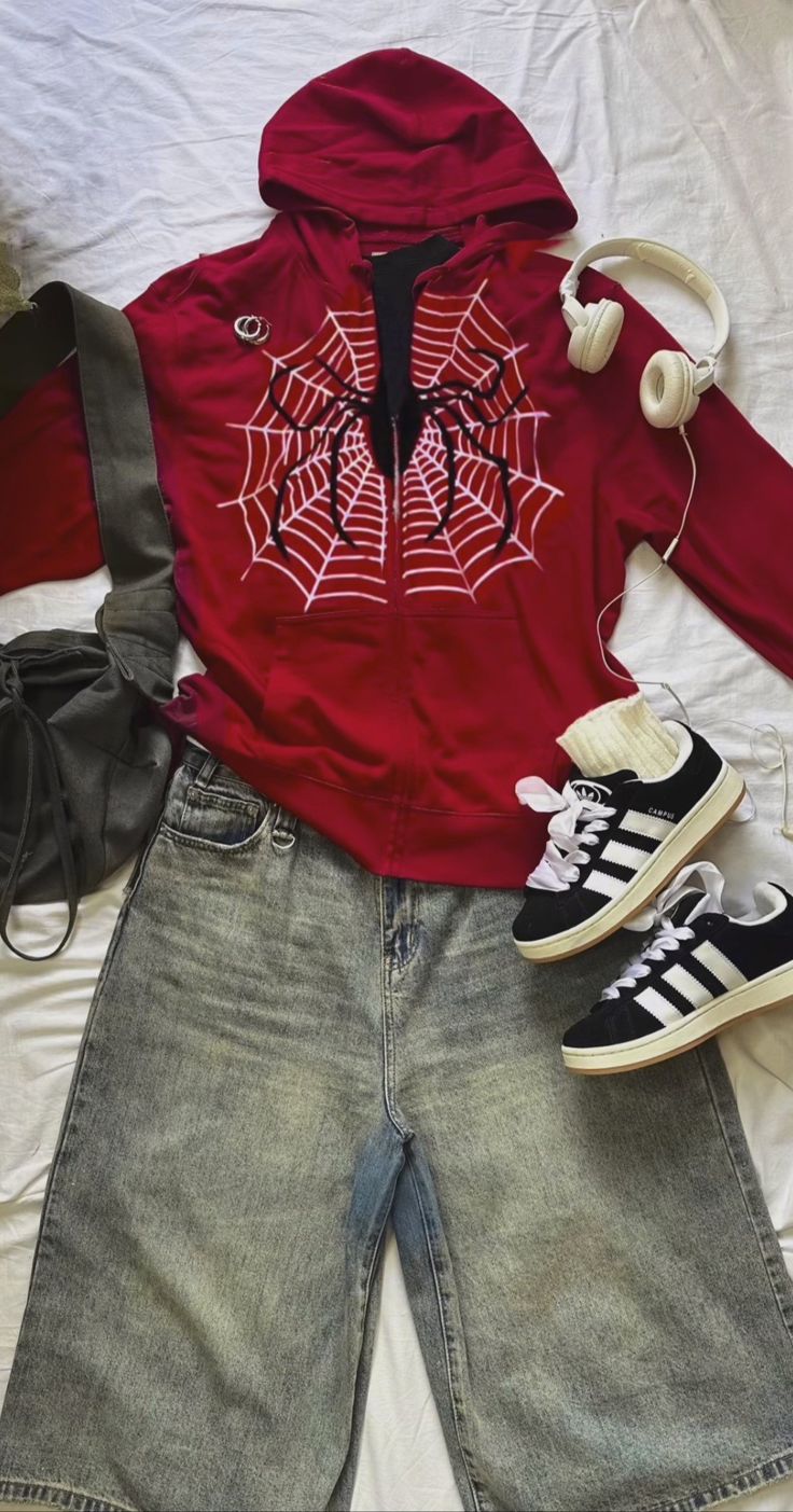 a red hoodie with spider webs on it and headphones laying next to shoes