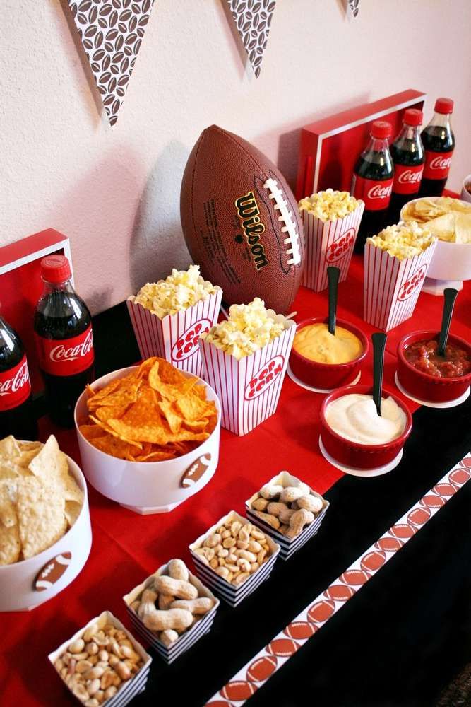 a football themed party with snacks, dips and crackers on a red table cloth