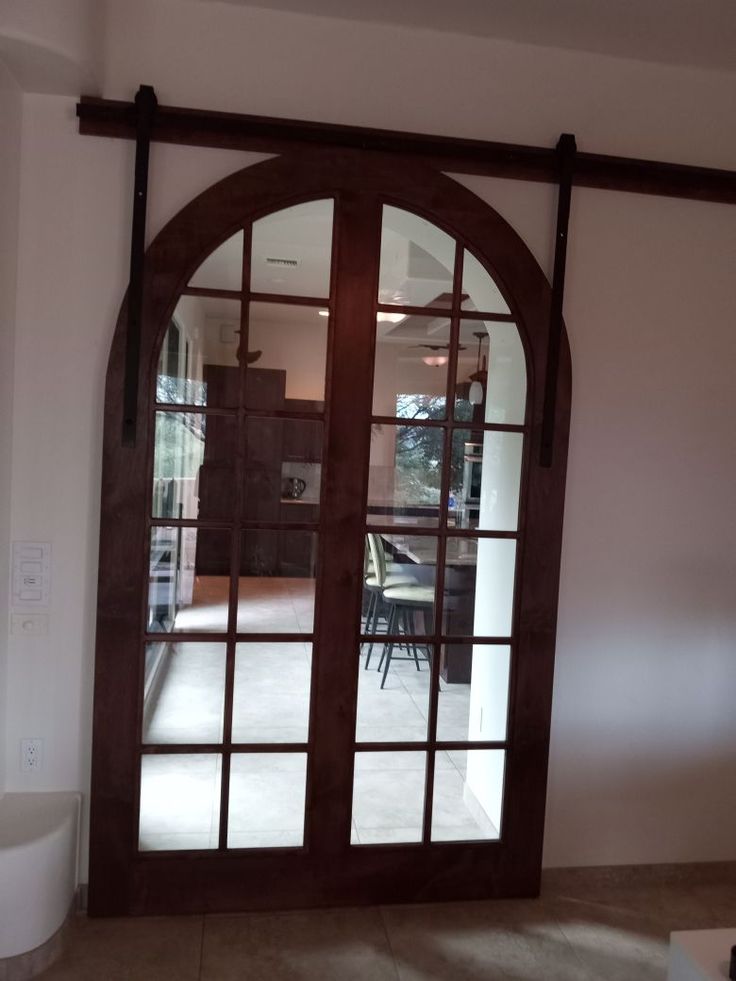 an arched glass door in the middle of a room with a dining table and chairs