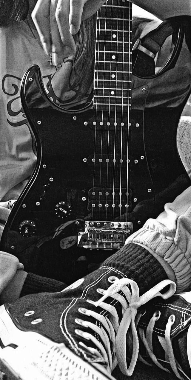 black and white photograph of a person playing an electric guitar with their feet on the ground