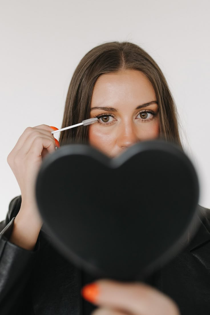 a woman holding a heart shaped object in front of her face