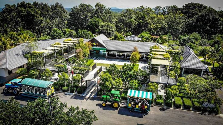 an aerial view of a house surrounded by trees and other greenery, with tractors parked in the driveway