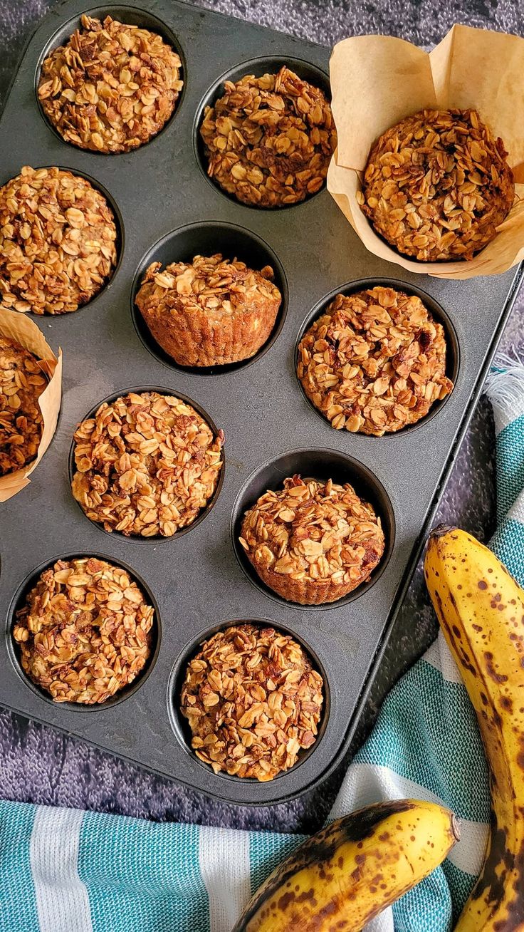 muffins and bananas sitting on a towel next to a cupcake tin filled with oatmeal