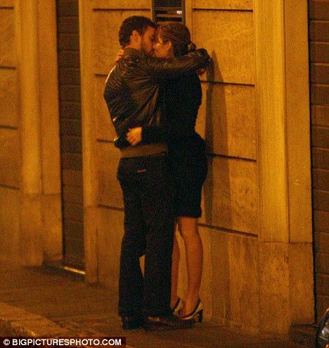 a man and woman hugging on the street corner at night with their arms around each other