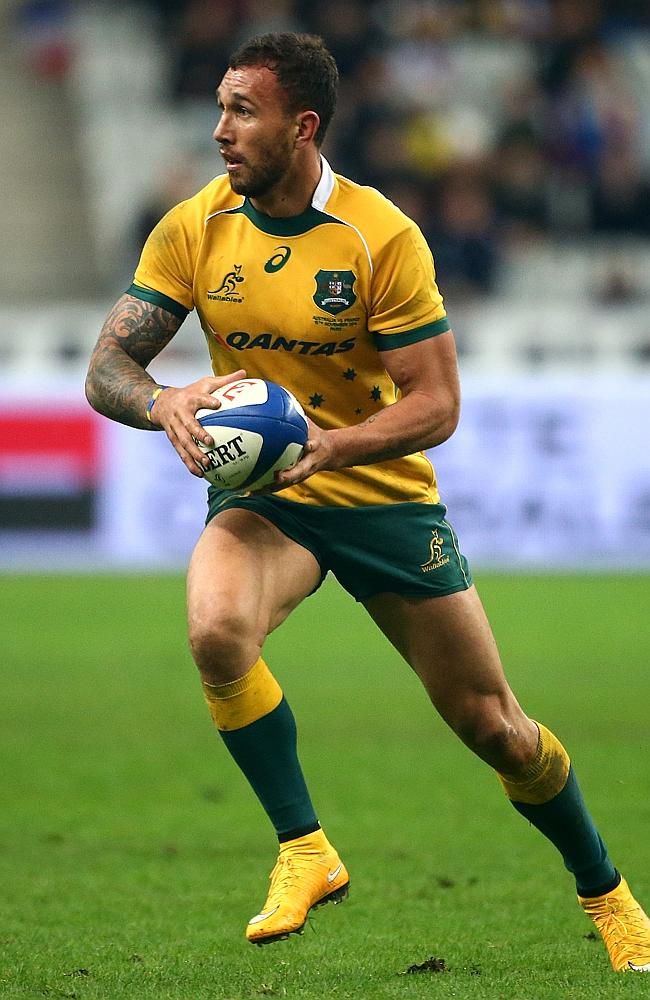 a rugby player is running with the ball in his hand and looking at the camera