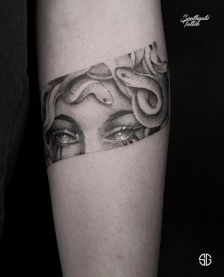 a black and white photo of a woman's face with snakes on her arm