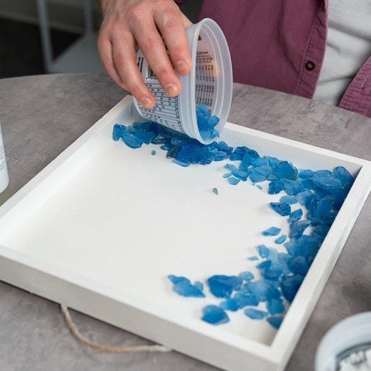 a person pouring blue paint onto a white tray