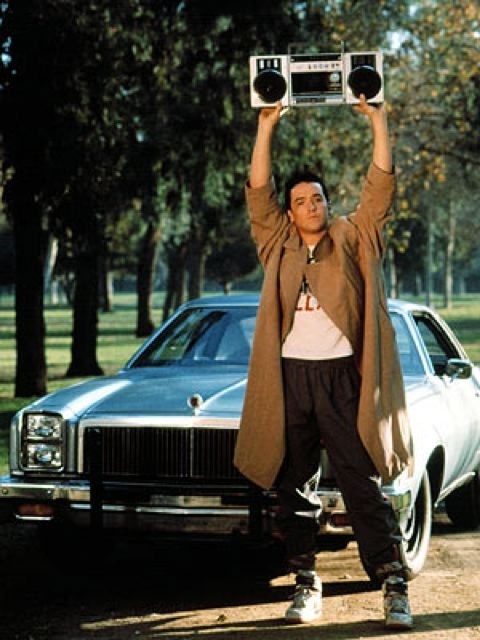 a man standing next to a car holding up two radio's over his head