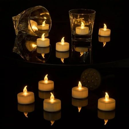 many lit candles on a black table in front of a glass container with some water