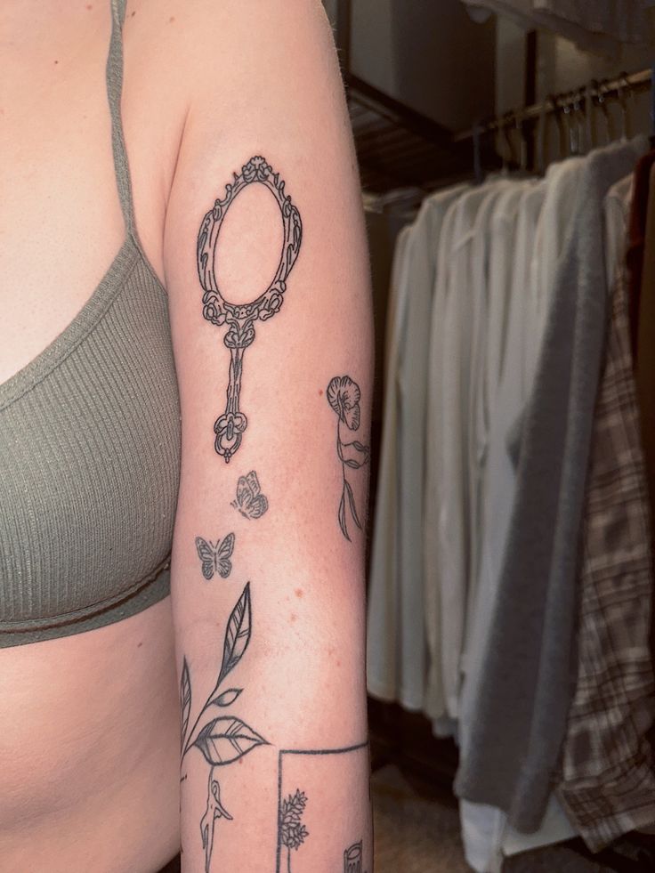 a woman's arm with tattoos on it and a mirror in the middle of her arm