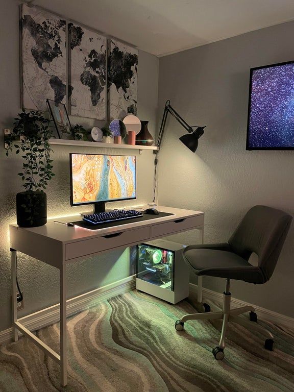 a computer desk with a monitor and keyboard on it in front of a wall mounted map