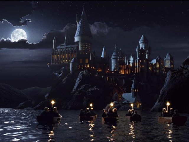 there are many people on the water in front of hogwart's castle at night