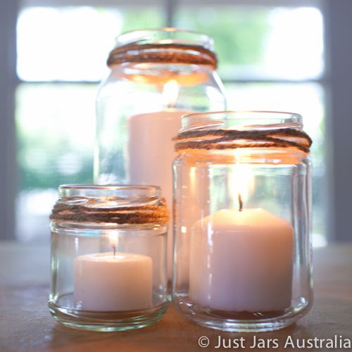 three glass jars filled with candles on top of a table