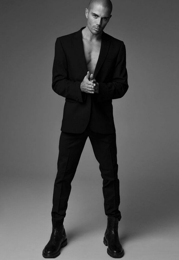 a shirtless man in a black suit posing for a magazine cover shoot with his hands on his hips