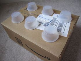 a cardboard box filled with plastic cups and saucers on top of carpeted floor