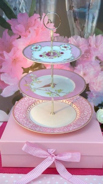 three tiered cake stand with pink flowers and polka dot napkins on the table