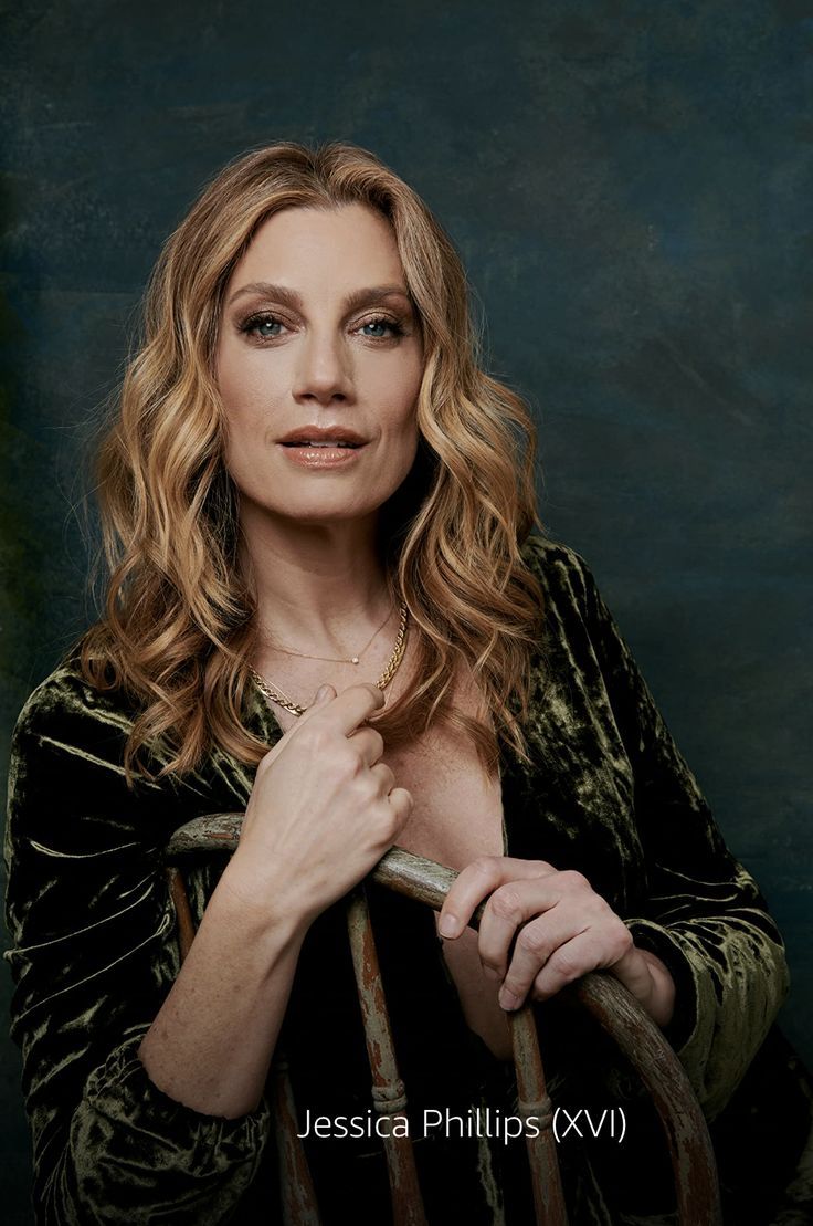 a woman is posing for a portrait with her hand on the back of an old chair