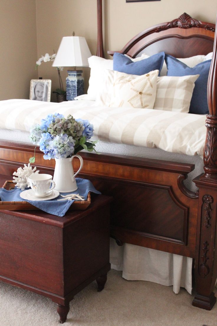 a bedroom with a bed, nightstand and flowers on the end table in front of it