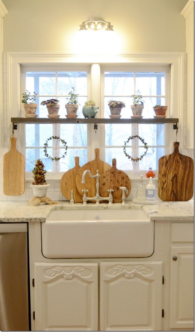 a kitchen sink with cutting boards on the window sill