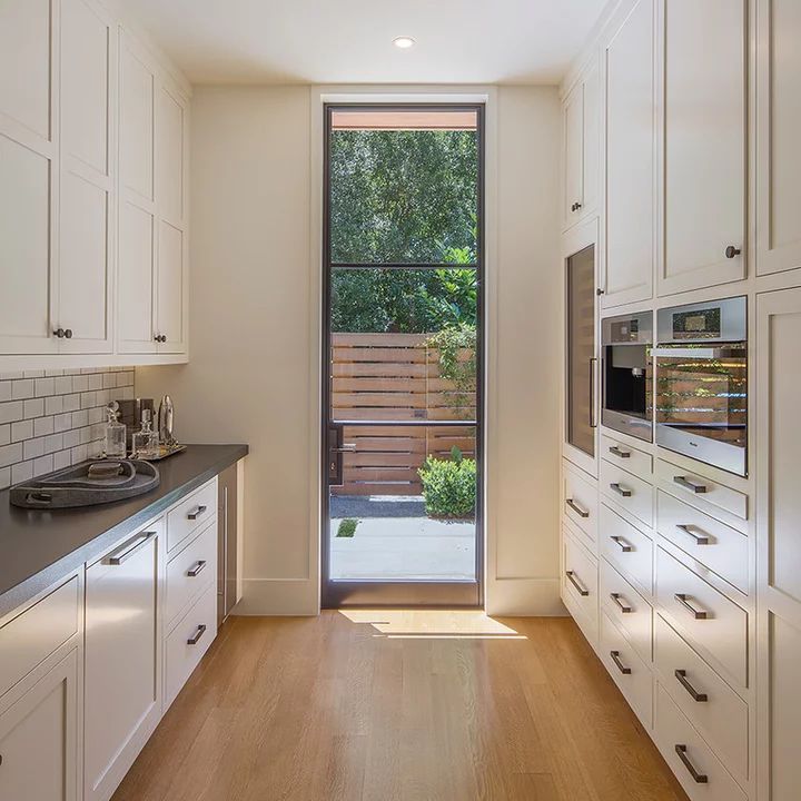 a kitchen with white cabinets and black counter tops next to an open door that leads to a deck