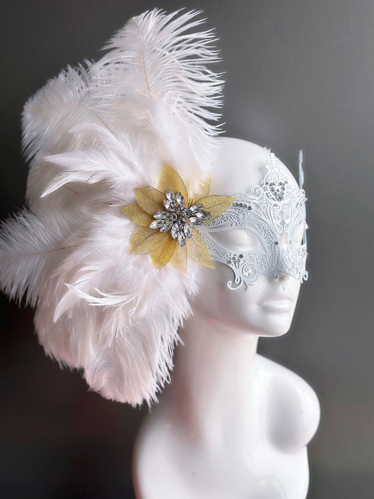 Our women's white laser cut metal masquerade mask, adorned with delicate white feathers and a gold crystal brooch, offers you the opportunity to add a touch of enchanting gold glitter to the mask. Whether you're attending a grand masquerade ball, a themed gala, or simply looking to add a touch of elegance to your attire, this mask ensures you'll be the center of attention. Age Group/Gender - Adult/Women Size/Type - One size fits all adults Mask Color - White Mask Material - Laser cut metal Elegant White Masquerade Mask For Carnival, White Eye Mask For Masquerade, Elegant White Masquerade Mask For Mardi Gras, Elegant White Masquerade Mask For Weddings, Elegant White Masquerade Mask, White Wedding Eye Mask, White Eye Mask For Wedding, Elegant White Eye Mask, Elegant White Wedding Masquerade Mask