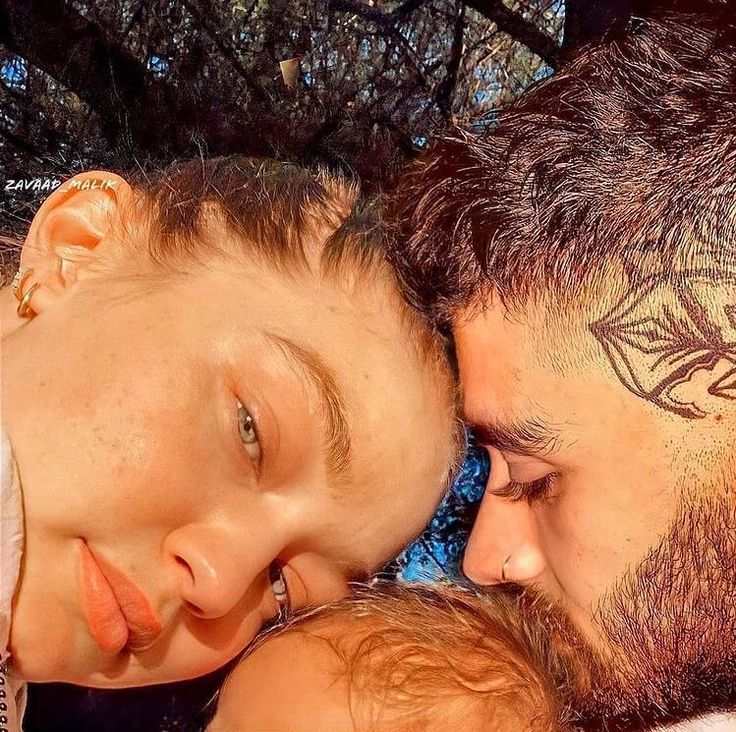 a man and woman with tattoos on their foreheads kissing each other in front of trees