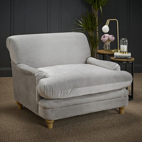 a gray chair sitting on top of a carpeted floor next to a table with flowers