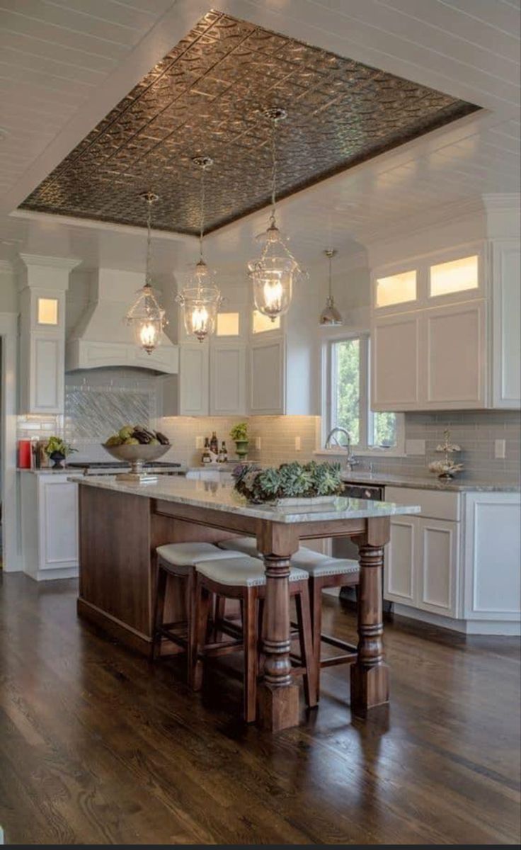 a large kitchen with an island and two stools next to it on a hard wood floor