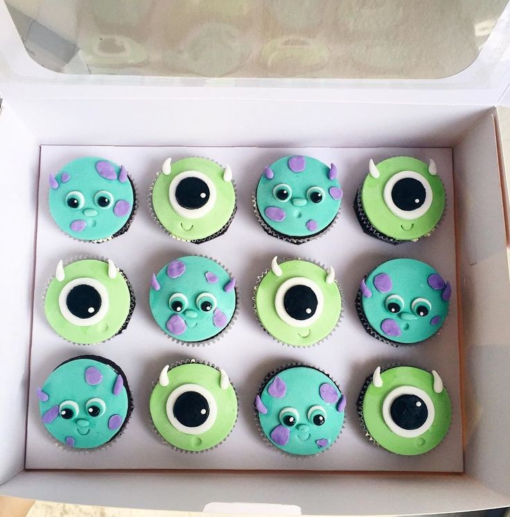 there are twelve cupcakes with green and blue frosting in a box on the table