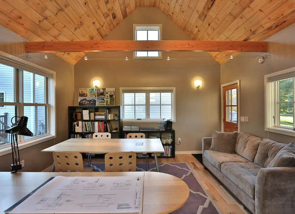 a living room with two couches and a table in the middle, surrounded by windows