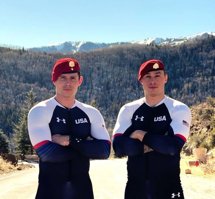 two men standing next to each other with their arms crossed in front of the camera